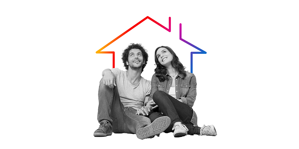 pareja feliz sentada en el suelo con la silueta de color de una casa detrás
