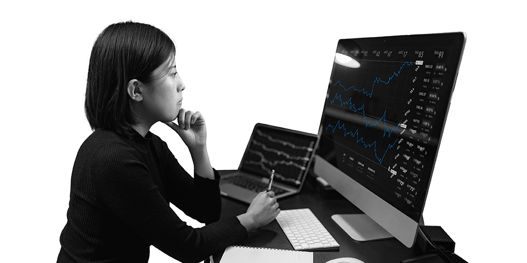 mujer mira pensativa un gráfico en un monitor mientras agarra un bolígrafo
