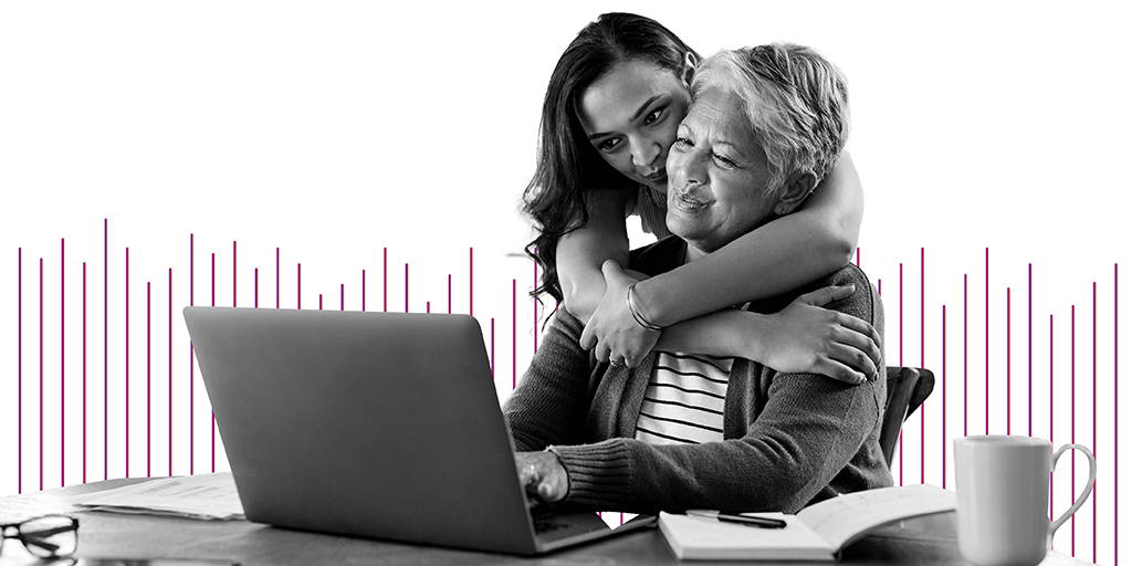 mujer mayor con su hija abrazándola miran un portátil